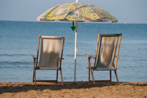 Zwei Holzliegen mit Sonnenschirm am Strand