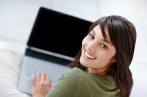 Porträt einer glücklichen jungen Frau, die einen Laptop verwendet