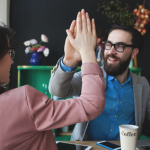 Modern team celebrating success giving five with laptop