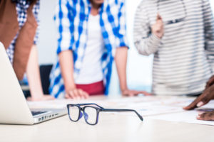 Advertising agency team in creative meeting, focus on glasses in foreground