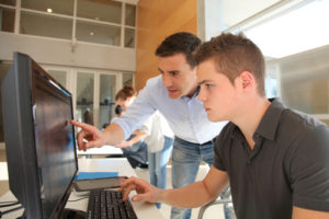Lehrer und Schüler arbeiten am Computer