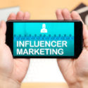 Aufpassen der Hand zwei, Handy mit Influencer-Marketing zu halten