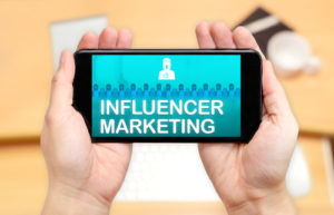 Aufpassen der Hand zwei, Handy mit Influencer-Marketing zu halten