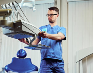 Zahnarzt in einem Raum mit medizinischer Ausrüstung auf Hintergrund.