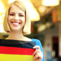 Nettes blondes Mädchen, das Flagge von Deutschland hält