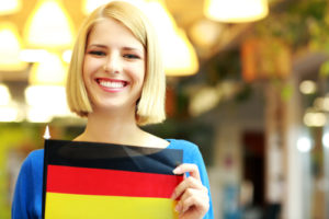Nettes blondes Mädchen, das Flagge von Deutschland hält