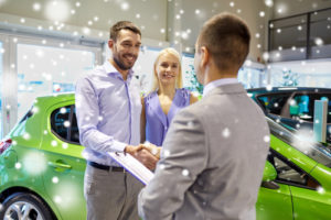 glückliches Paar mit Autohändler in Auto Show