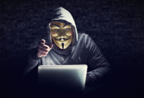 Hacker mit Maske am Laptop