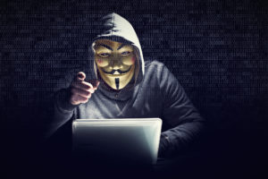 Hacker mit Maske am Laptop