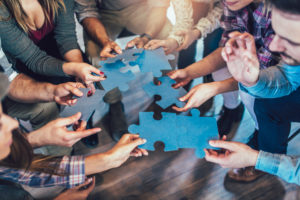 Wirtschaftler, die sich Puzzlespielstücken im Büro, Abschluss oben anschließen.