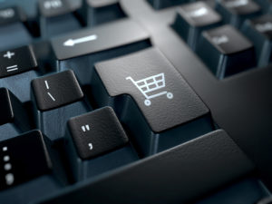 Nahaufnahme einer Tastatur mit der Eingabetaste durch ein Warenkorb-Symbol ersetzt. E-Commerce-Konzept