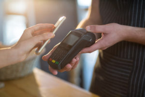 Frau, die Rechnung durch Smartphone unter Verwendung NFC-Technologie zahlt