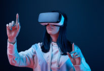Frau mit Virtual Reality-Brille streckt Finger in die Höhe