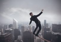 Businessmann balanciert auf Seil über Hochhäuser