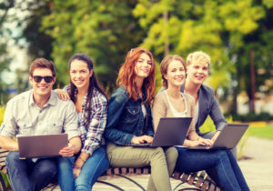 5 junge Leute mit Laptop auf einer Parkbank