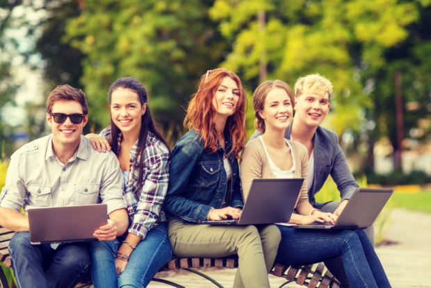 5 junge Leute mit Laptop auf einer Parkbank