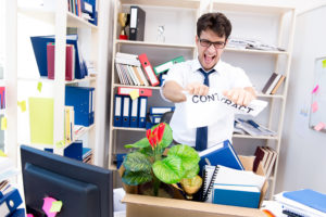 Geschäftsmann, der von seinem Job gefeuert wurde, zerreisst im Büro ein Zettel mit Aufschrift Contract