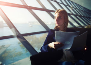 Business Frau mit Papieren schaut aus Fenster