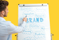 Junger Businessmann zeigt auf Flipchart mit Aufschrift Brand