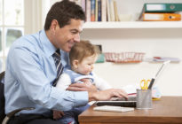 Businessmann mit Baby am Laptop zuhause