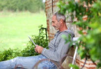 Älterer Mann auf einer Bank mit Tablet