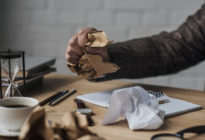 Männliche Hand zerknüllt Papier auf Schreibtisch