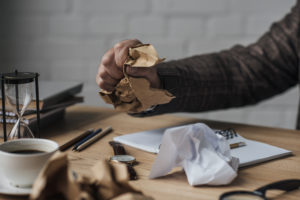 Männliche Hand zerknüllt Papier auf Schreibtisch