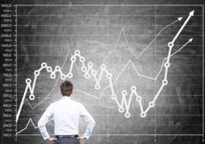 Businessmann steht vor Tafel mit Chart