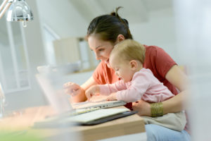 Businessfrau arbeitet mit Baby an Laptop