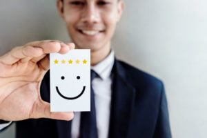 Businessmann, der Karte mit Smiley in der Hand hält