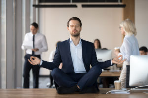 Businessmann meditiert auf Schreibtisch