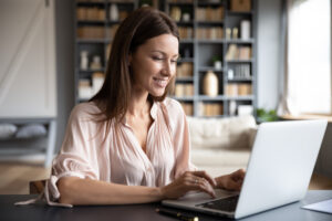 Junge Frau sitzt am Schreibtisch vor einem Laptop im Home-Office