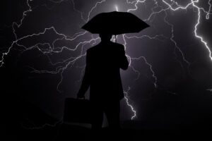 Businessmann mit Regenschirm im Gewitter