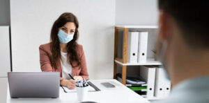 Businessfrau mit Maske im Büro