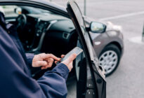 Männliche Hand mit Smartphone vor seinem Auto