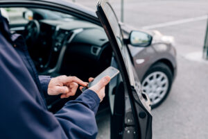 Männliche Hand mit Smartphone vor seinem Auto