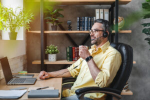 Homeoffice: Mann mit Headset und Laptop am Schreibtisch Zuhause