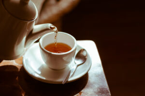 Teekanne, aus der Tee in eine Teetasse gefüllt wird