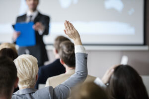 Rückansicht einer Geschäftsfrau, die eine Hand während einer Präsentation hebt