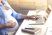 Schwangere Frau am Schreibtisch mit Laptop