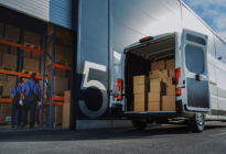 Arbeiter mit Kartons und Lieferwagen außerhalb eines Logistik-Distributionslagers