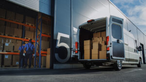 Arbeiter mit Kartons und Lieferwagen außerhalb eines Logistik-Distributionslagers
