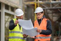 Junger Asiate und Ingenieuer auf Baustelle lesen Bauplan
