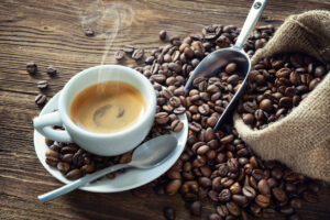Tasse dampfender Kaffee mit Kaffeebohnen und Schaufel