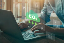 Männerhände an Laptop, darüber ist Schild mit Aufschrift CO2 Reduktion