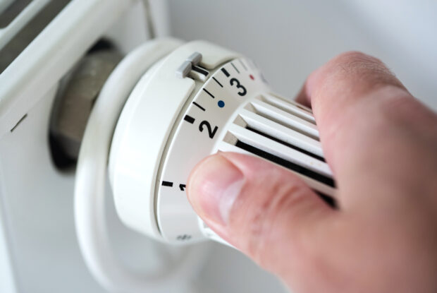 Energiekrise: Hand dreht Thermostat herunter