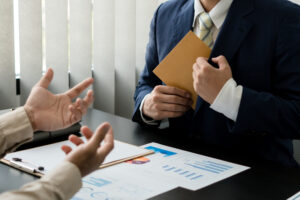 Businessmann steckt Briefkuver ein, das ihm andere Hände gegeben haben