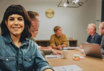 Junge Businessfrau im Meeting mit ihren Arbeitskollegen an einem Tisch