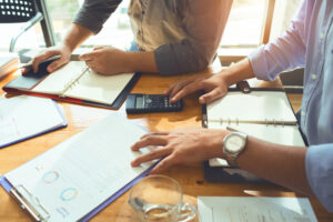 Zwei Personen sitzen gemeinsam am Tisch und arbeiten mit Unterlagen
