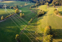 Stromtrasse, die durch Wald- und Wiesenlandschaft führt